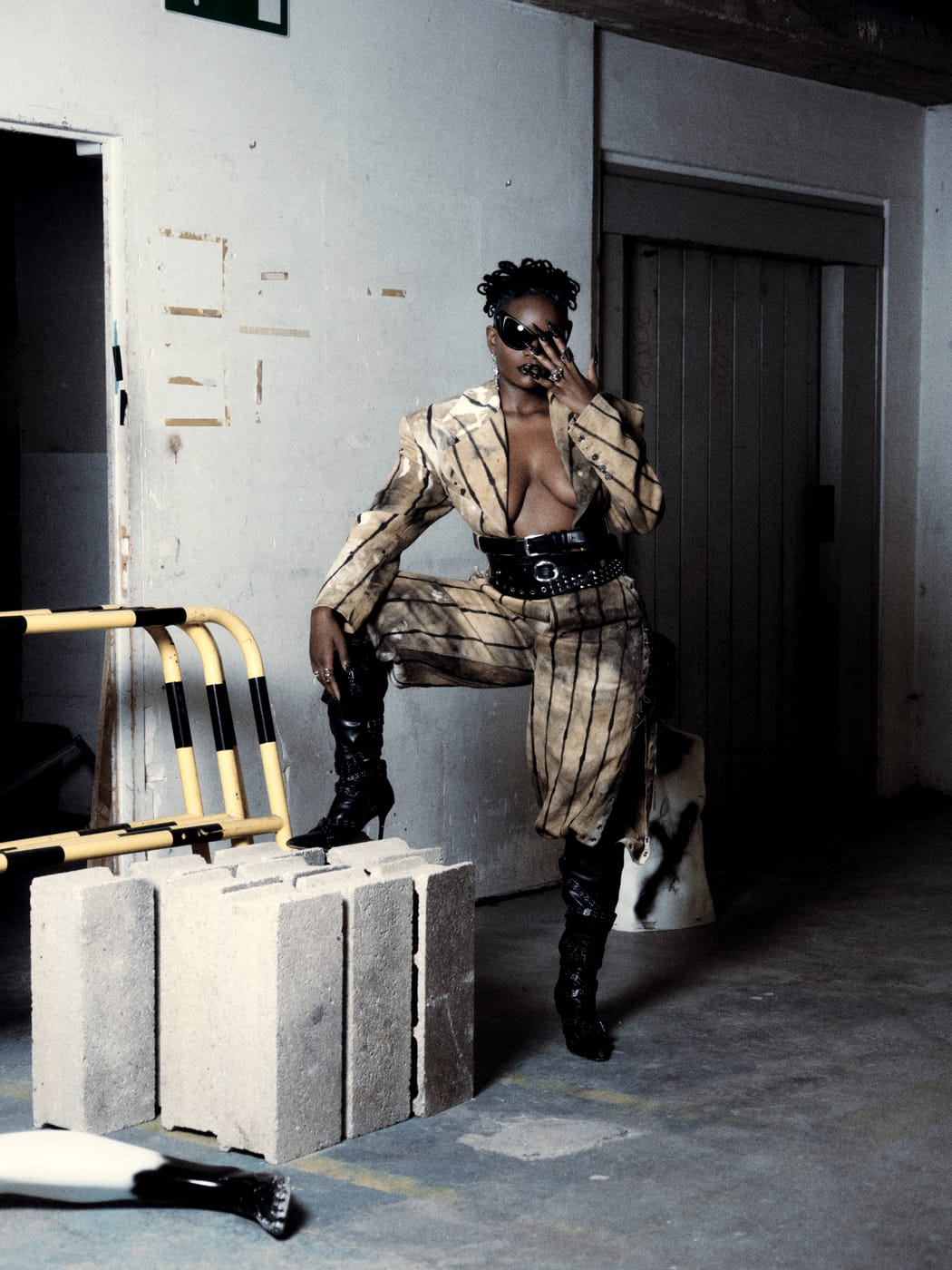Ezek in the striped suit, one boot up on the cinder blocks, hand to her face