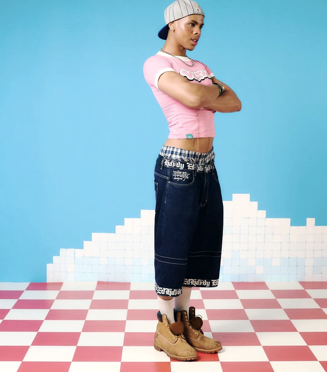 Oluwa arms crossed in the pink Recessland shoot, pixel-cloud backdrop